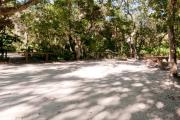 Side view of sandy site sixteen showing picnic table, fire ring and wooden railings nestled under shady maritime hammock in Anastasia State Park.