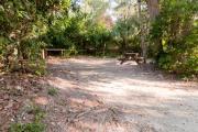 Picnic table and wooden railing nestled under the shady maritime hammock on site 23âs sandy pad in Anastasia State Park.