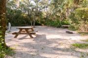 Picnic table, electric hookup and fire ring nestled under the shady maritime hammock on site 27âs sandy pad in Anastasia State Park.