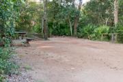 Side view of sandy site 92 showing picnic table, lantern post and water hookup with live oak trees nestled under shady maritime hammock in Anastasia  State Park.