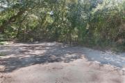 Side view of sandy site 96 showing picnic table, lantern post and electric and water hookups with live oak trees nestled under shady maritime hammock
