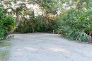 Frontal view of sandy site 97 showing lantern post and electric and water hookups with live oak trees nestled under shady maritime hammock in Anastasia State Park.