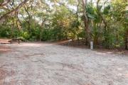 Frontal view of sandy site 102 showing picnic table, lantern post and electric and water hookups with live oak trees nestled under shady maritime hammock in Anastasia State Park.