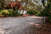 Side view of sandy site 102 showing picnic table, lantern post and electric and water hookups with live oak trees nestled under shady maritime hammock in Anastasia State Park.