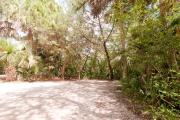 Side view of sandy site 107 showing picnic table, electric and water hookups with live oak trees nestled under shady maritime hammock in Anastasia State Park.