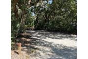 Rear view of sandy site 122 showing picnic table and fire ring nestled under the shady live oak trees and maritime hammock in Anastasia State Park.