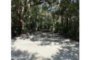 Frontal view of sandy site 122 showing electric and water hookups with live oak trees nestled under shady maritime hammock in Anastasia State Park.
