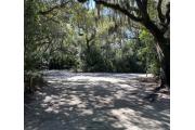 Side view of sandy site 122 showing picnic table with live oak trees nestled under shady maritime hammock in Anastasia State Park.