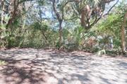 Side view of sandy site 121 showing electric and water hookups with live oak trees nestled under shady maritime hammock in Anastasia State Park.