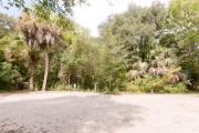 Side view of sandy site 130 showing electric and water hookups with live oak trees nestled under shady maritime hammock in Anastasia State Park.