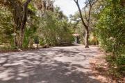 Frontal view of paved site 133 showing picnic table, hibachi and easy paved access to bathhouse with live oak trees nestled under shady maritime hammock in Anastasia State Park.