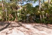 Side view of sandy site 134 showing electric and water hookups with live oak trees nestled under shady maritime hammock in Anastasia State Park.