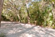 Side view of sandy site 138 showing electric and water hookups with live oak trees nestled under shady maritime hammock in Anastasia State Park.