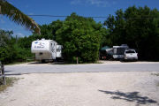 Photo: Buttonwood: Paved road with two campsites and campers on each site in background.