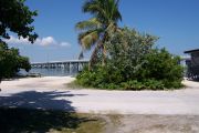 Photo: Buttonwood: Paved road with two campsites on the other side, bushes border sites, water and new Bahia Honda Bridge in the background.