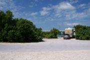 Photo: Buttonwood: Paved road with a campsite on the other side, bushes border site, water and new Bahia Honda Bridge in the background.