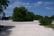 Photo: Buttonwood: Paved cul-de-sac with bushes in the middle, campsite on the left with silver camper, bushes border sites, new Bahia Honda Bridge in the background.