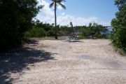 Photo: Buttonwood: Gravel campsite with picnic table, surrounded by bushes. Water and old Bahia Honda bridge in the background.