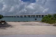 Photo: Buttonwood: Gravel site with picnic table and grill, bushes, water and new Bahia Honda Bridge in the background.