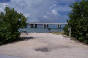 Photo: Buttonwood: Gravel site with picnic table and grill, bushes, water and new Bahia Honda Bridge in the background.