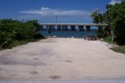 Photo: Buttonwood: Gravel site with picnic table and grill, bushes, water and new Bahia Honda Bridge in the background.