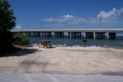 Photo: Buttonwood: Gravel site with picnic table and grill, bushes on left side, water and new Bahia Honda Bridge in the background.