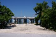 Photo: Buttonwood: Gravel site with picnic table and grill, bushes on either side, water and new Bahia Honda Bridge in the background.