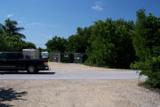 Photo: Buttonwood: Paved road with small gravel parking lot across road, dumpsters and vehicles in back ground.