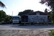Photo: Buttonwood: Paved road with an occupied campsite and bathhouse across road, bushes in back ground.