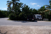 Photo: Buttonwood: Paved road with an occupied campsite in background and bushes around site