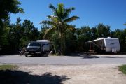 Photo: Buttonwood: Paved road with two occupied campsites in background and bushes around sites
