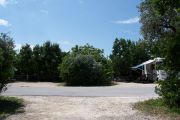 Photo: Buttonwood: Paved road with one empty site and one occupied site in background and bushes around sites