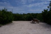 Photo: 074, BAYSIDE:Small gravel campsite with picnic table surrounded by trees.