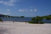 Photo: 074, BAYSIDE: Gravel road with wood fence, boating basin and bushes in the background, cabin on the left.