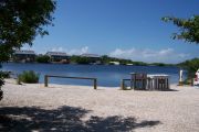 Photo: 076, BAYSIDE: Gravel road with wood fence, boating basin, bushes and cabins in the background.