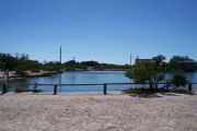 Photo: 077, BAYSIDE: Small gravel campsite with picnic table and grill, surrounded by trees.