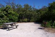 Photo: 078, BAYSIDE: Small gravel campsite with picnic table and grill, surrounded by trees.
