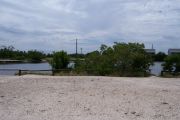 Photo: 079, BAYSIDE: Gravel road with wood fence, boating basin, bushes and cabins in the background.