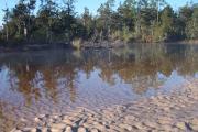 Early morning steam rises above the river with curving sand ripples along the brown, sandy bank.