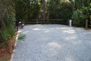 A view of the campsite with a shell/sand base and partial shade.