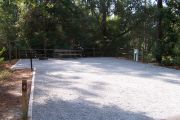 A view of the campsite with a shell/sand base and partial shade.