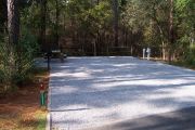A view of the campsite with a shell/sand base and partial shade.