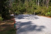 A view of the campsite with a shell/sand base and partial shade.