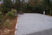 A view of the campsite with a shell/sand base and partial shade.