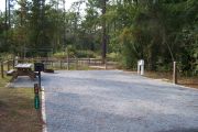 A view of the campsite with a shell/sand base and partial shade.