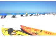 Blue beach umbrellas dot Caladesiâs white sandy beach with two sea kayaks in the foreground.