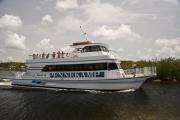 Photo: JOHN PENNEKAMP CORAL REEF SP. âSpirit of Pennekamp,â the Parkâs glass bottom boat brings visitors sitting on top deck to marina, with first mate on bow and orange life raft on top of white boat with name painted on side; green mangrove trees, white clouds and light blue sky in background
