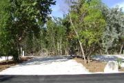 Photo: 006, JOHN PENNEKAMP CORAL REEF SP. Rock with campsite number, partially shaded gravel campsite with picnic table, grill, concrete sewer hookup basin, electric post, and paved road in foreground.