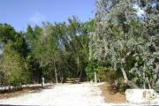 Photo: 009, JOHN PENNEKAMP CORAL REEF SP. Rock with campsite number, no shade gravel campsite with picnic table, grill, concrete sewer hookup basin, electric post, and paved road in foreground.