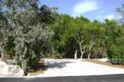 Photo: 010, JOHN PENNEKAMP CORAL REEF SP. Rock with campsite number, almost no shade gravel campsite with picnic table, grill, concrete sewer hookup basin, electric post, and paved road in foreground.